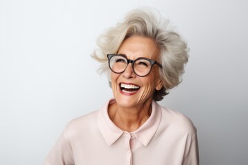 Portrait of a happy senior woman with eyeglasses against grey background