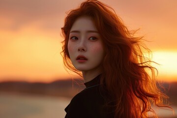 A full body photo of a Korean girl, captured in the golden hour light. Her face, framed by soft, wavy red hair, glows with a warm,