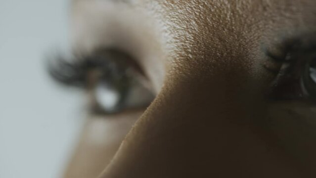 Macro shot of female model face. African American woman shot cropped face, green eyes looking away from camera.