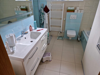 designer bathroom with glossy turquoise tiles. green and white combination even on a striped towel drying on a radiator. rair comb. advertising for dental and body cosmetics and products.