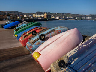 detail shot of some colourful boats placed upside down on the promenade next to the beach in the...