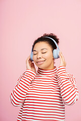 Beautiful overjoyed African American woman wearing headphones listening to music with eyes closed