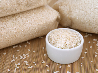White rice in a white bowl near bags of rice.