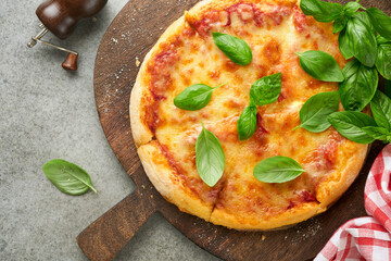 Margarita pizza. Traditional neapolitan margarita pizza and cooking ingredients tomatoes basil on old concrete texture background table. Italian Traditional food. Top view. Mock up.
