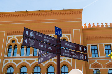 Tourist info sign with directions in front of old gymnasium in Mostar, street sign