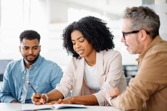 Engagement and teamwork in an office where a woman in a white blazer engages in a lively discussion with her colleagues, analyzing documents or making strategic planning together