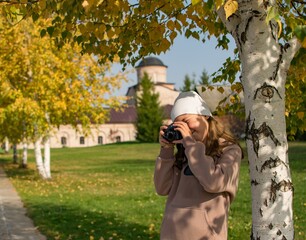 A ten-year-old girl photographs the sights at the monastery on an autumn day