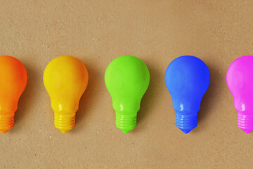 Light bulbs in different colors on recycled paper background - Concept of creativity and divergent...