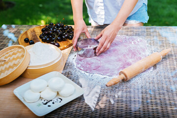 A woman is using a rolling pin on a table to prepare food. Mochi asian dessert