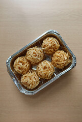 close up of Chinese New Year deep fried taro nests snacks in a tin foil container