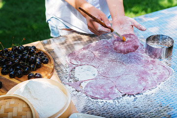 A person is preparing food by cutting dough on a table. Mochi asian dessert