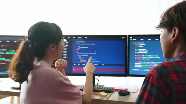 Slow motion back end software developer engineer for computer programming working together on debugging writing computing code, solving complex algorithms display on monitor in office. Burgeoning