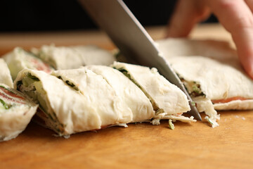 A pita roll is cut with a knife on a cutting board. Lavash dish.
