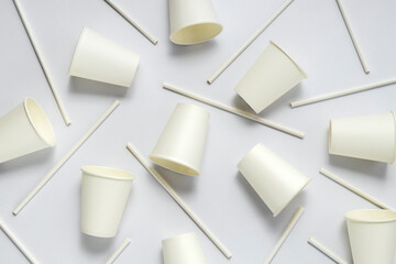 Top view of white paper cups and straws on the light backfround.Empty and clean.Net zero consumtion