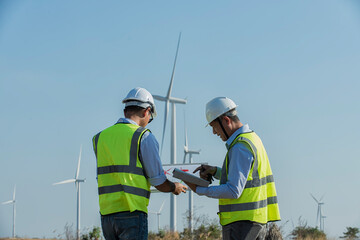 Service engineers checking wind turbine on tablet on wind turbine farm Power Generator on background Station on mountain, Thailand people