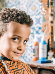 Moroccan boy smiling and looking at the camera with a hairdresser in the background.