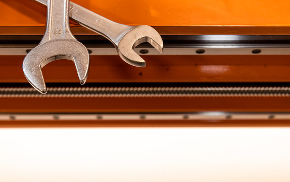 wrenches on a CNC machine are orange, the shaft and guide rails of the machine are visible
