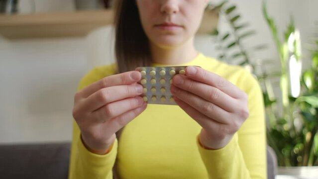 Selective focus of young woman hands holding hormonal oral contraceptive medicine, take pharmaceutical to prevention, safe virus sex disease, contraception, menstruation concept, birth control pills