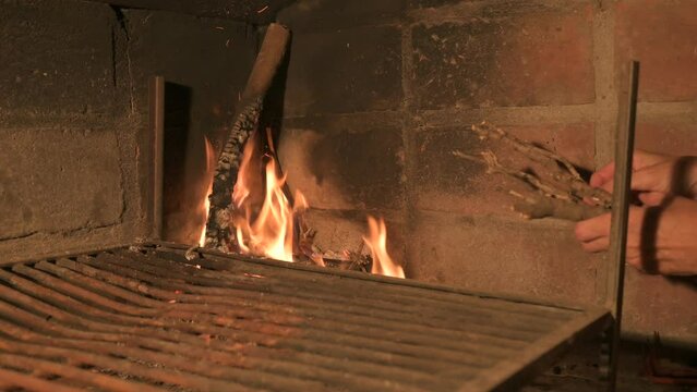 Poniendo le&ntilde;a/ramas al fuego para la parrilla