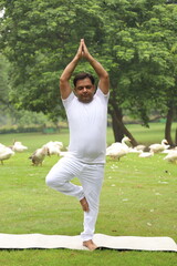 A young obese man exercising and doing Yoga poses in a green serene environment early morning in a park to maintain a healthy lifestyle. Fit India