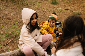 Mommy taking a picture of her children in the forest with her cell phone.dng