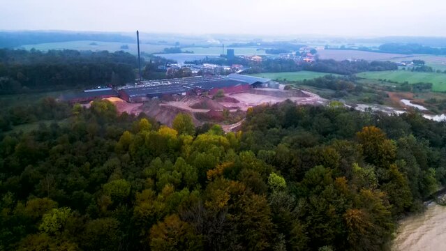 Industrieanlage am Rande eines herbstlichen Waldes mit Ausgrabungsst&auml;tte bei d&auml;mmrigem Tageslicht. Drohnen Reveal Shot. Ziegelei Fisken&aelig;svej, Graasten, D&auml;nemark