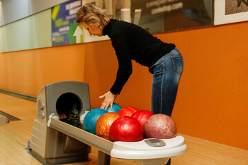 Fototapeta premium A middle-aged woman in a bowling club selects bowling balls