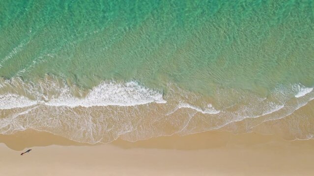 A perfect beach with nobody, in a sunny day and with colorful water, sea and ocean with litle waves; view from a drone shot