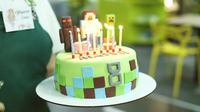 Female hand lights 8 candles on a cake for a boy. birthday celebration