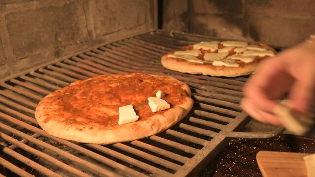 Poniendo queso cortado arriba de una pizza a la parrilla