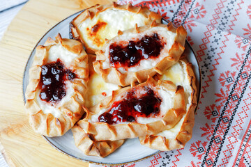 Karelian plays or Karjalanpiirakka. Traditional finnish or north russian pastry with cottage cheese and jam on clay plate. Flat lay.