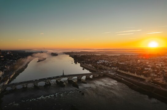 Horizons Embrace: A Mesmerizing Sunset Over the Flowing River and Majestic Bridge