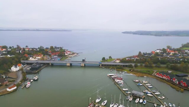 Luftansicht einer Kleinstadt mit Zugbr&uuml;cke &uuml;ber einen Fluss und angedockten Segelbooten. Drohnenaufnahme. Egernsundbr&uuml;cke, Sildekule in Egernsund, D&auml;nemark.