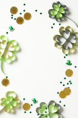 St Patrick's Day frame of four leaf clover paper art, gold coins, confetti on white background.