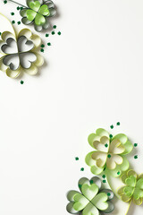 Frame of four leaf clover paper art with confetti on white vertical background. St Patrick's Day...