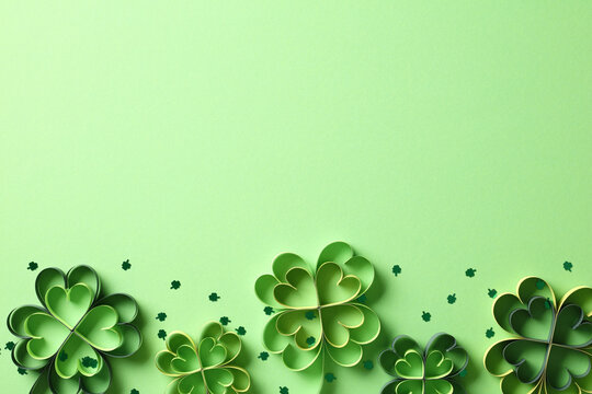 St Patrick's Day four leaf clover paper art on green background with confetti. Top view. Flat lay.