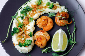 Close up scallops served with garnish mashed potatoes on black plate. Flat lay.