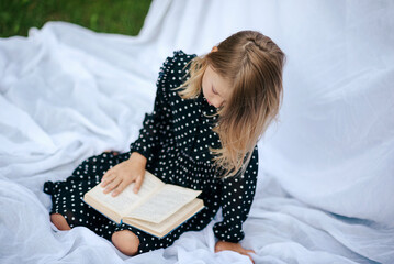 Portrait of happy child. Little beautiful girl reads book