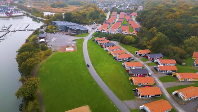 Drohnenansicht eines Autos in einer Ferienhaussiedlung mit roten D&auml;chern neben einem Fluss im Herbst. Drohnenaufnahmen, Marina Fisken&aelig;s, Graasten, D&auml;nemark