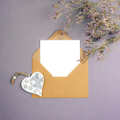 Envelope with blank card, vintage toy heart and flowers on gray background. Valentines day, womens day concept, top view, flat lay, mockup