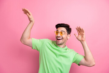 Photo of young man in sunglasses with green t shirt raised hands up looking empty space good vibes...