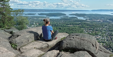 Woman enjoy panoramic view to Oslo Fjord from Kolsstoppen mountain. Mt. Kolsastoppen, popular hiking area with spectacular panoramic views of Oslo, Berum, and the Oslo Fjord.