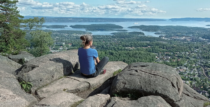 Woman enjoy panoramic view to Oslo Fjord from Kolsstoppen mountain. Mt. Kolsastoppen, popular hiking area with spectacular panoramic views of Oslo, Berum, and the Oslo Fjord.