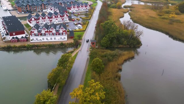 Drohne verfolgt Auto neben einer gepflegten Wohnsiedlung mit traditioneller Architektur neben einem nat&uuml;rlichen Wasserlauf. Drohnenaufnahme, Gravenstein, Graasten, D&auml;nemark