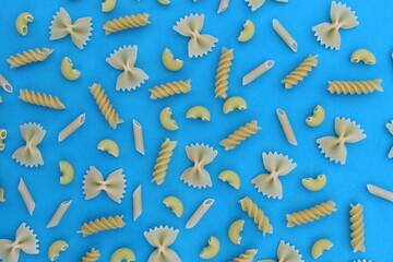 Abstract texture of different pasta on a blue background.