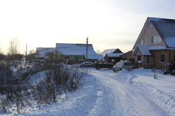 The village is covered with snow on a clear winter day.