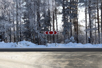 A road sign stands on a dead-end road in winter.