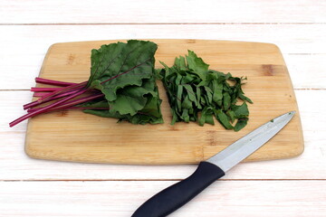 A chopped beet leaf lies on the table with a knife.