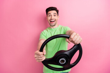 Photo of young professional driver food courier hold steering wheel hurry to deliver fresh meals isolated on pink color background