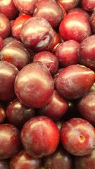 Close up pile of tasty fresh plums sold at the market as a background.